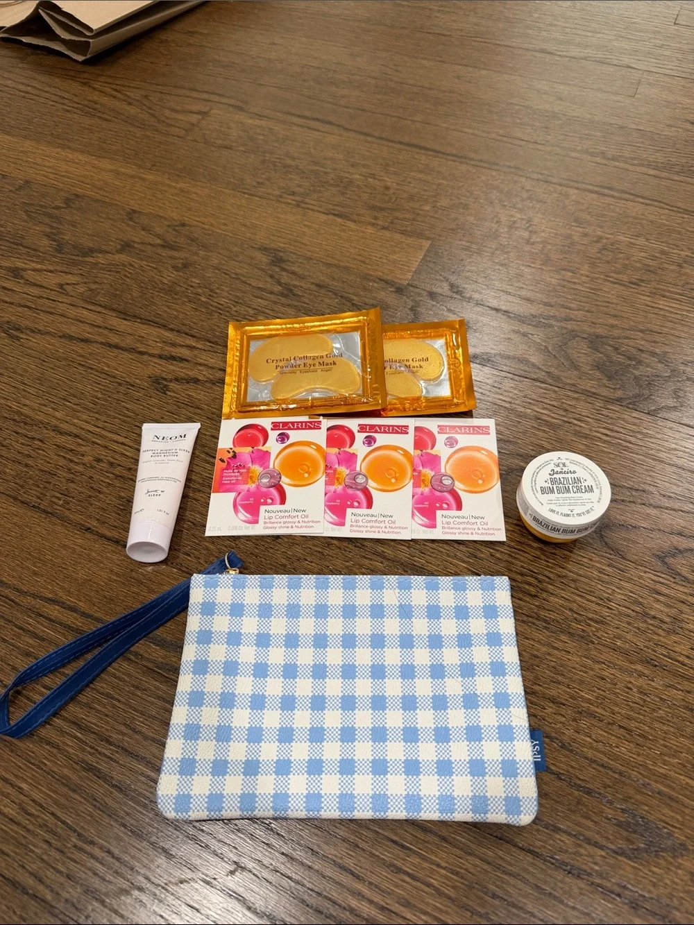 Gingham Wristlet with 2 body creams, 2 eye masks, 3 clarins lip oil samples
